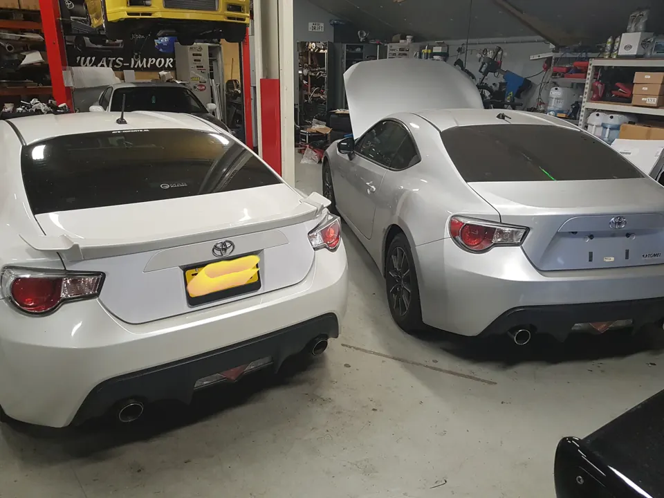 Two white sports coupes in the workshop