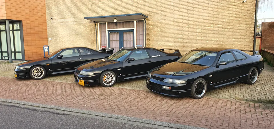 Three black Nissan Skyline R33 coupes